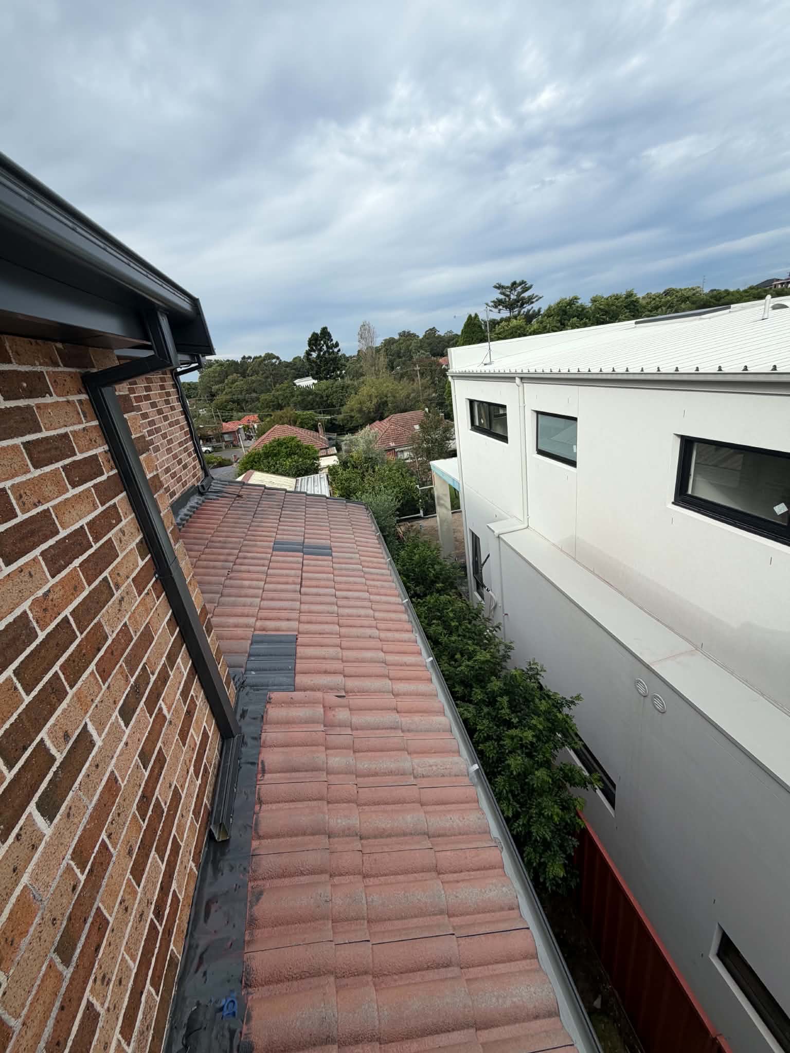 Terracotta roof section beside a brick wall before work