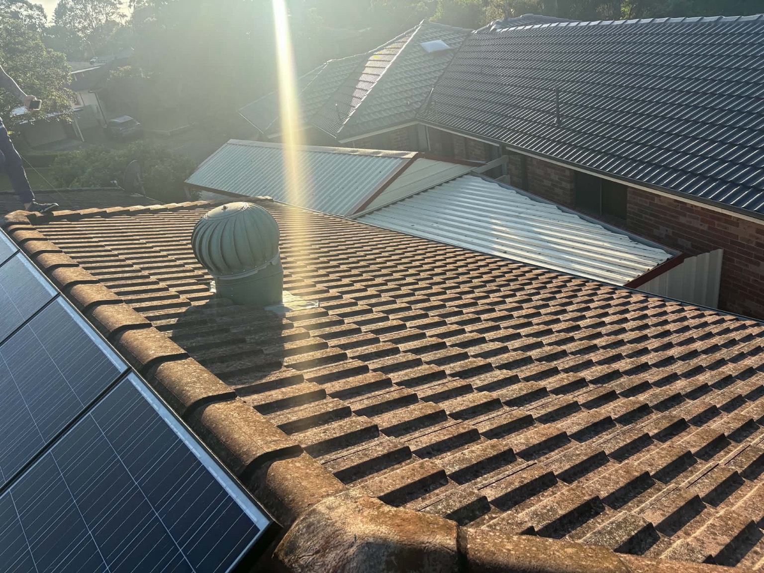 Weathered, discoloured tile roof with solar panels before restoration
